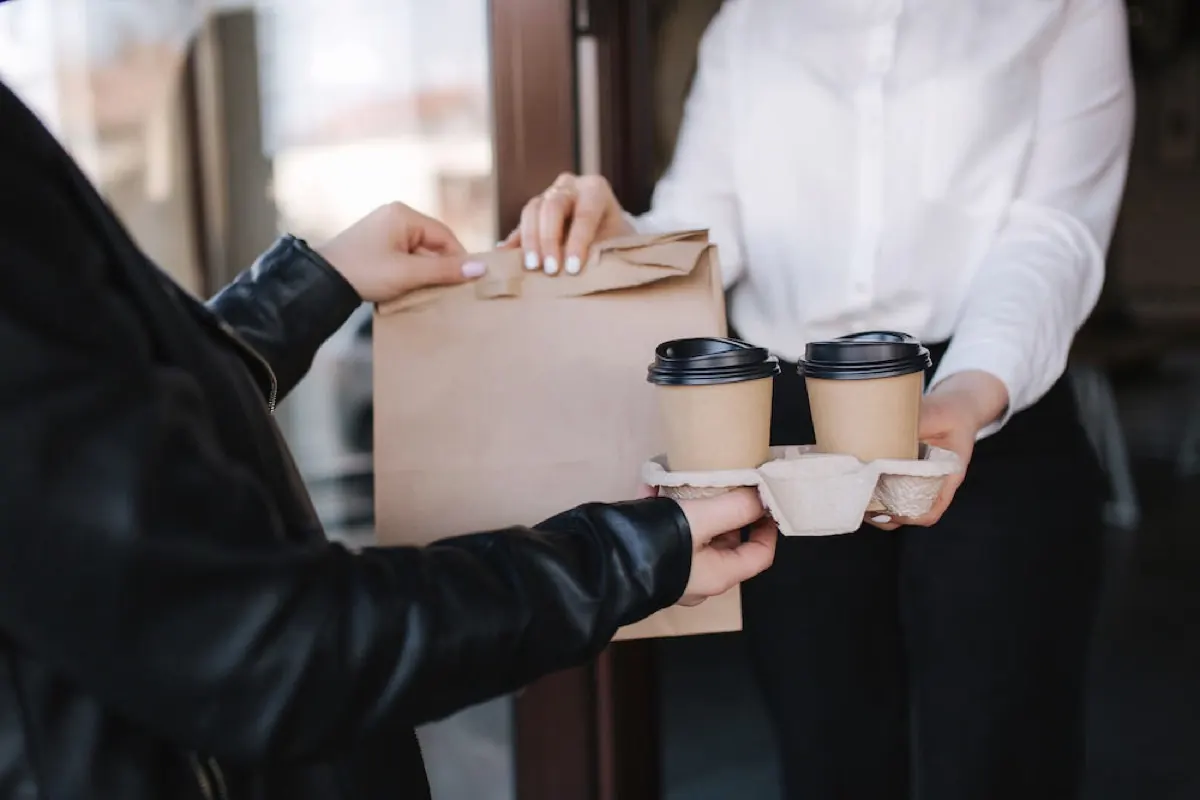 Consegna di una borsa e caffè da un esercente